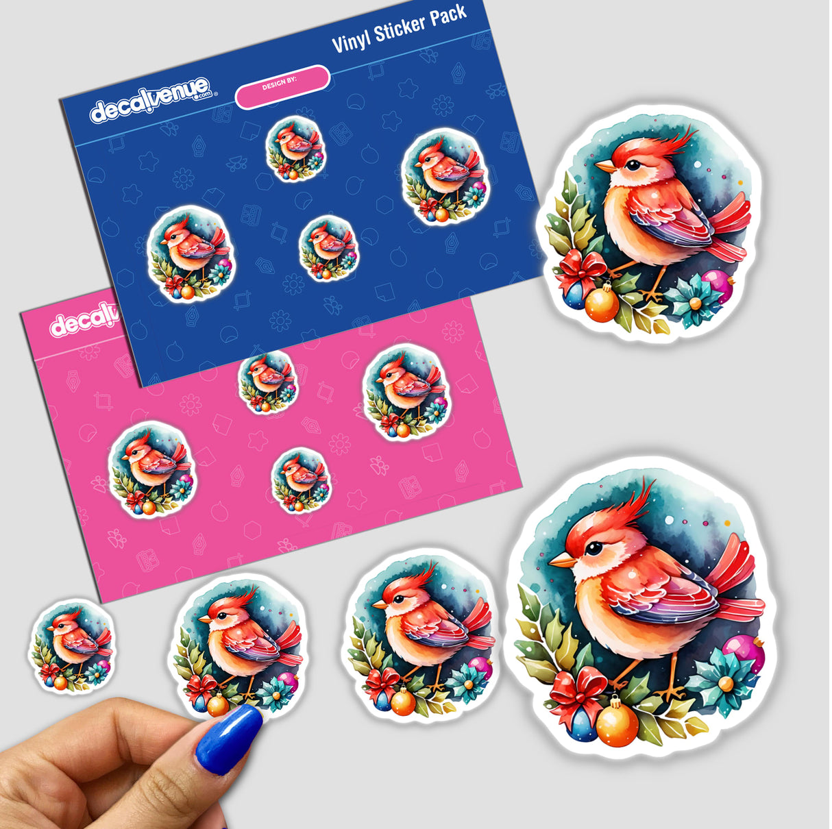 Sticker Design: Festive Christmas Bird Perched on a Holiday Wreath, shown in a pack of stickers with various bird designs and a hand with blue nail polish holding a sticker.