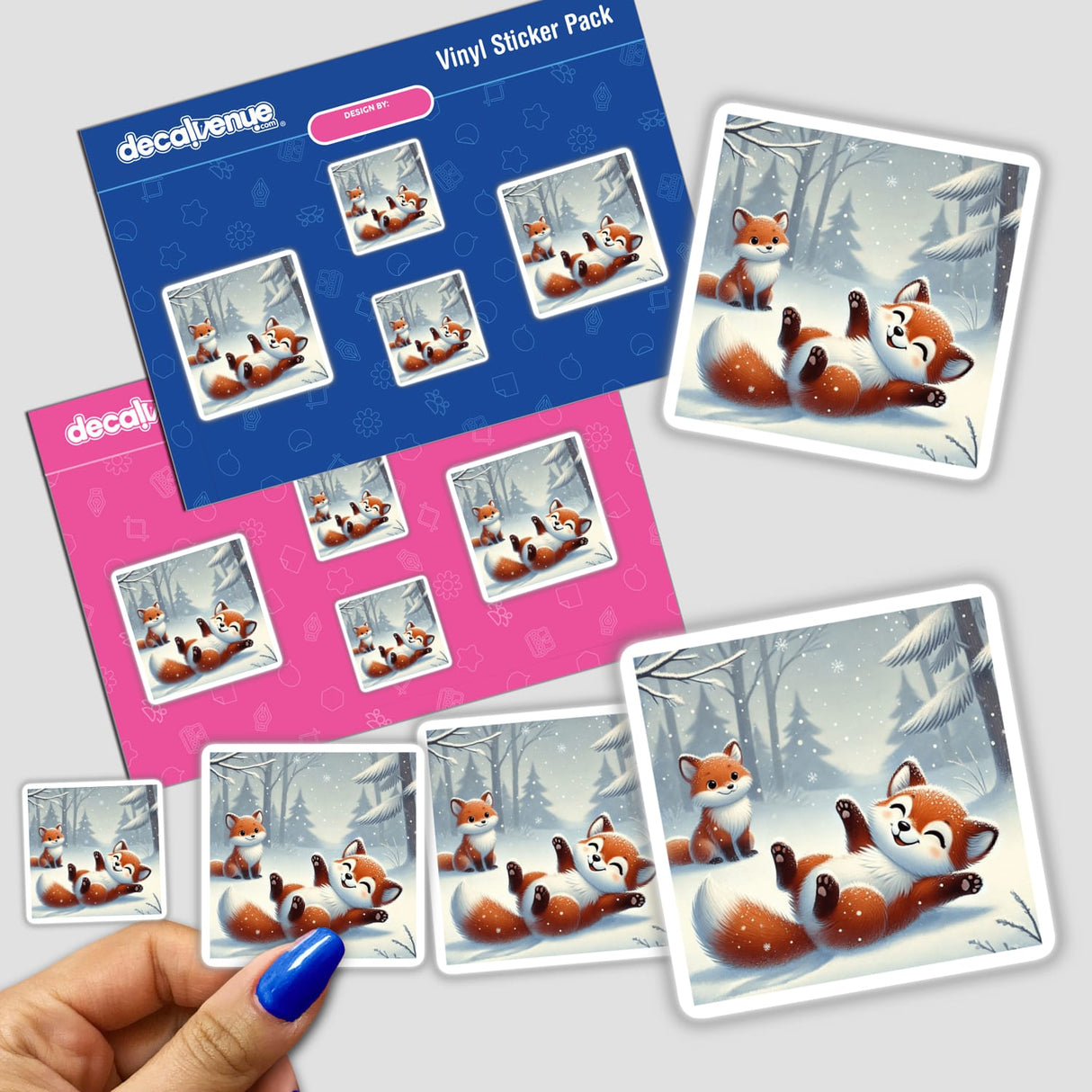 Two Foxes Playing sticker pack featuring cartoon foxes frolicking in snow, with a close-up of a hand holding a sticker. Ideal for Decal Venue's unique stickers and digital art collection.