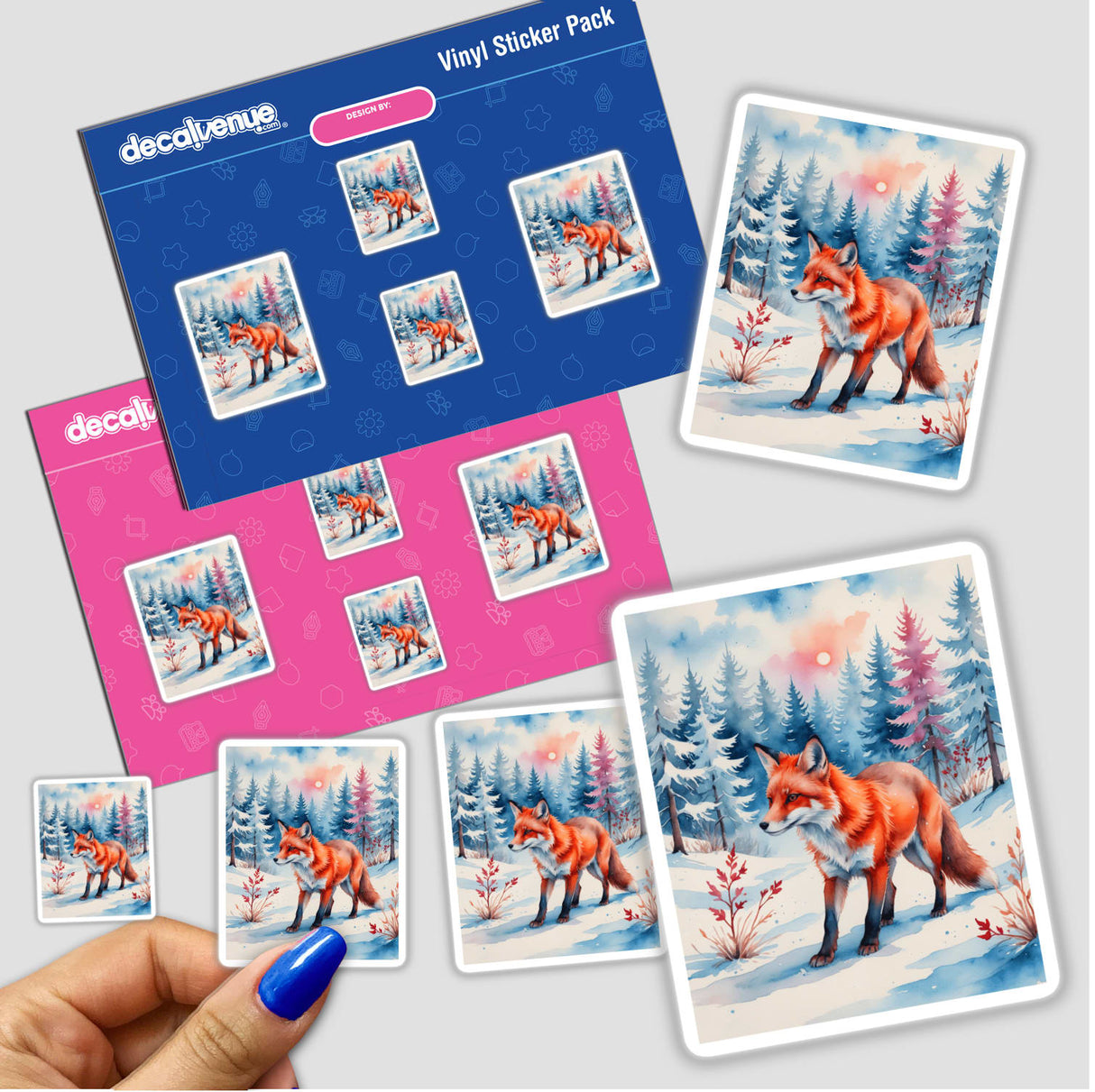 Hand holding 'A Red Fox In A Winter Forest' stickers, showcasing a fox amidst snowy scenes, available as unique vinyl stickers or digital artwork from Decal Venue.