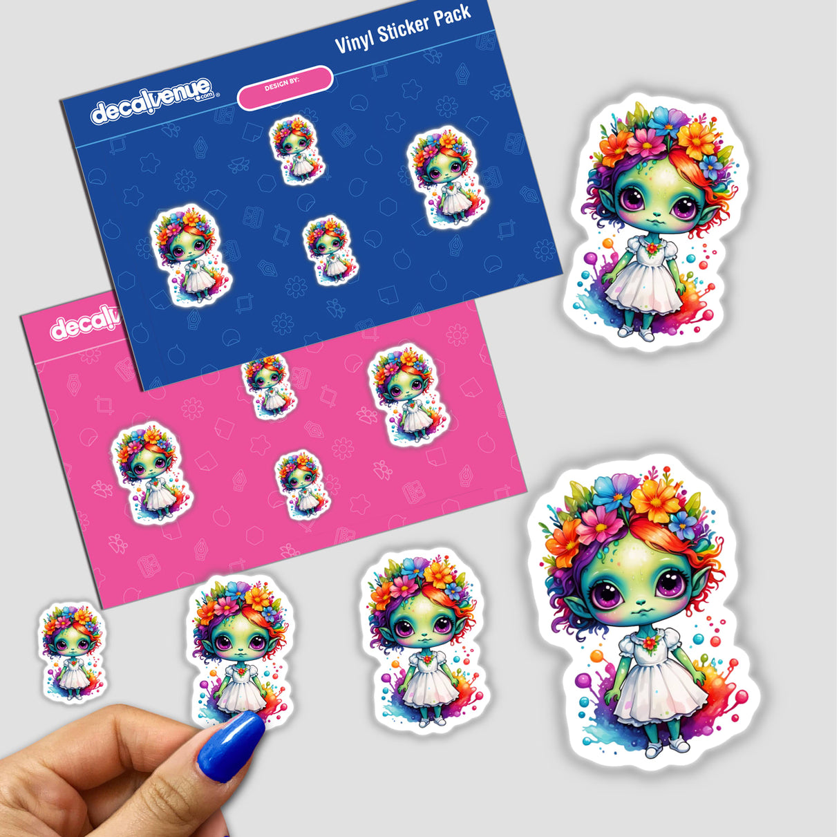 Hand with blue nail polish holding a pack featuring Extraterrestrial Elegance: Cute Alien in Floral Splash Dress Sticker, showcasing cartoon characters with floral accents.