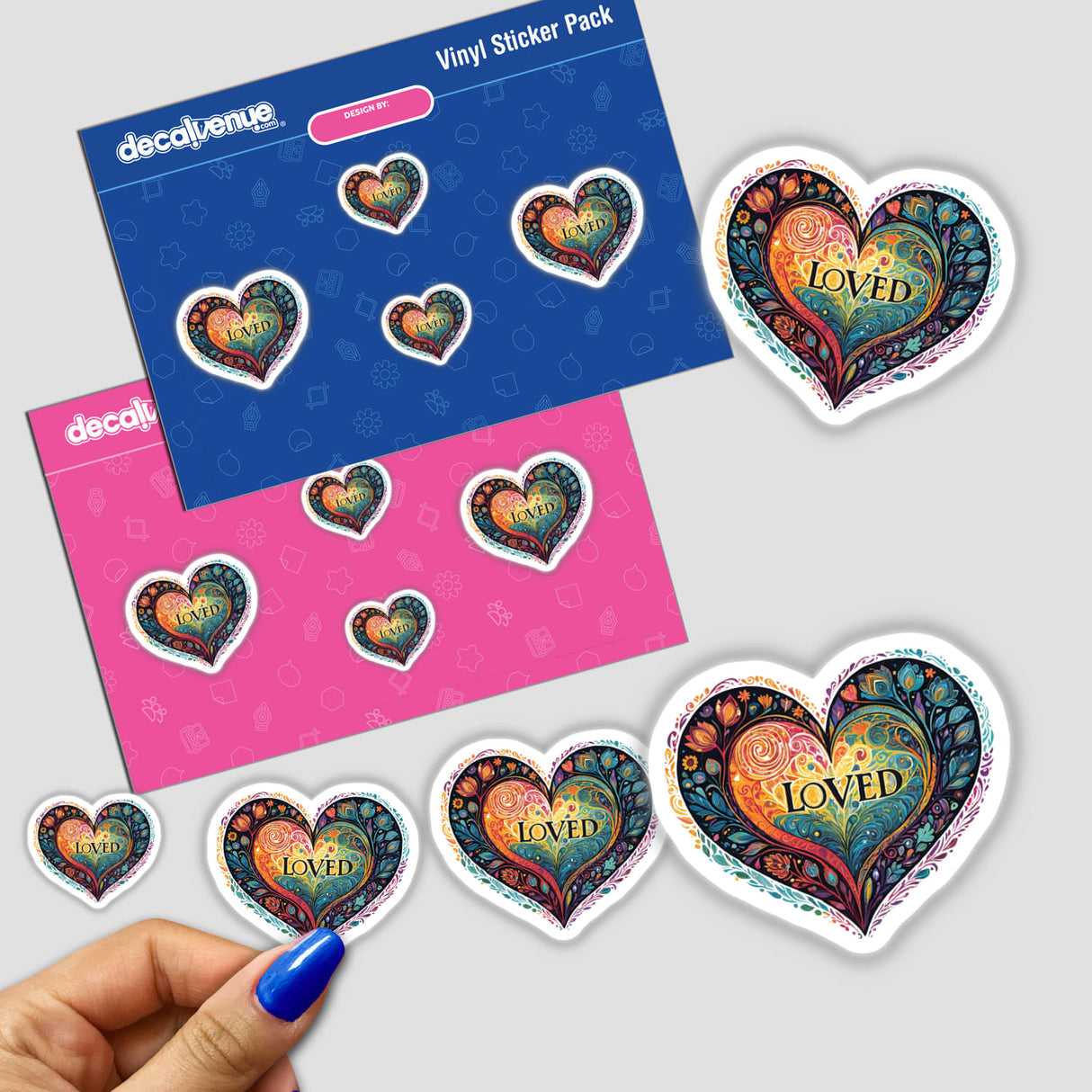 Colorful heart-shaped vinyl stickers featuring the word "Loved" on a decorative patterned background. The stickers are displayed on a pink and blue patterned sticker pack from the Decal Venue store.