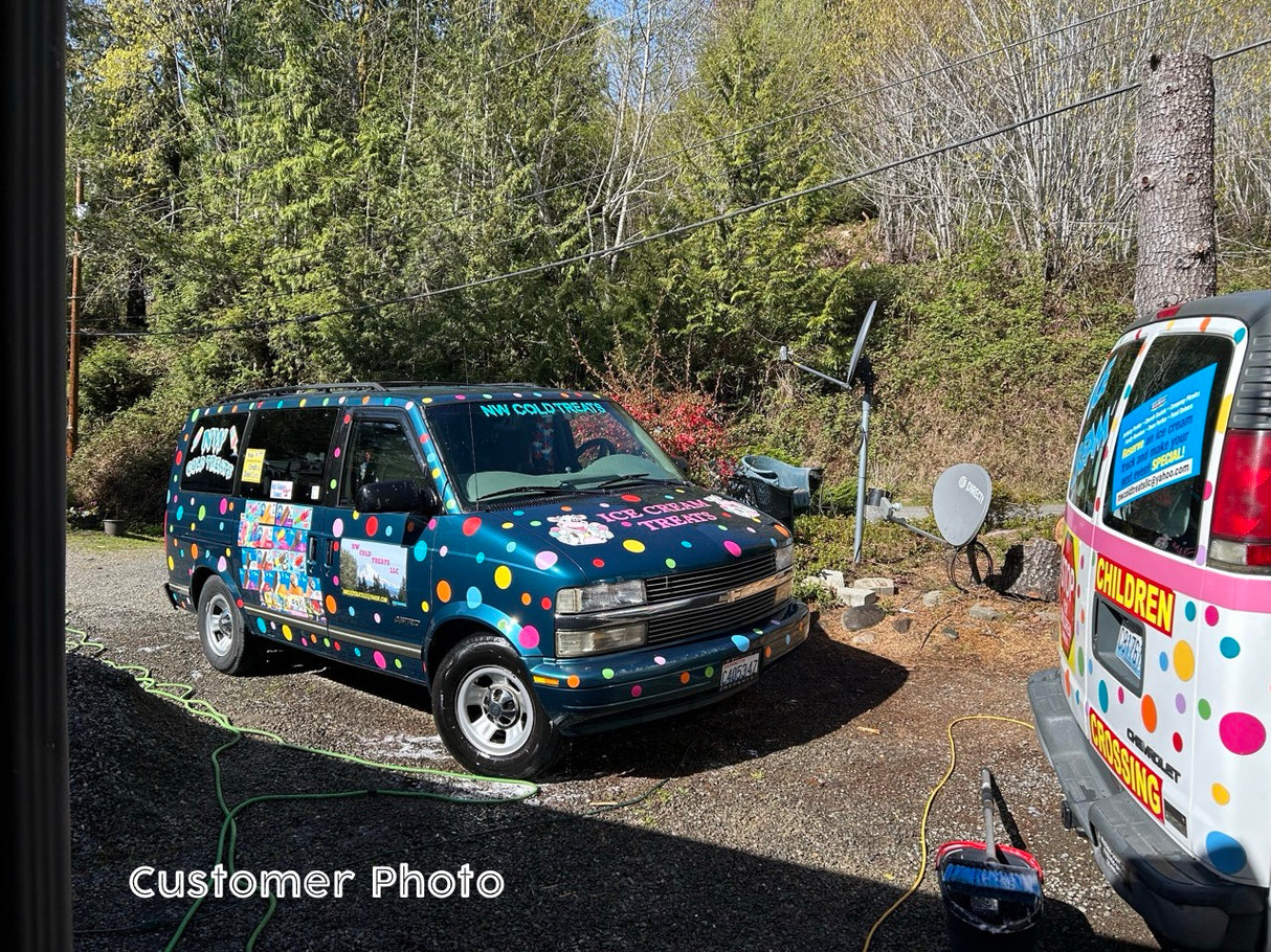 Colorful polka dot stickers on two vans surrounded by trees