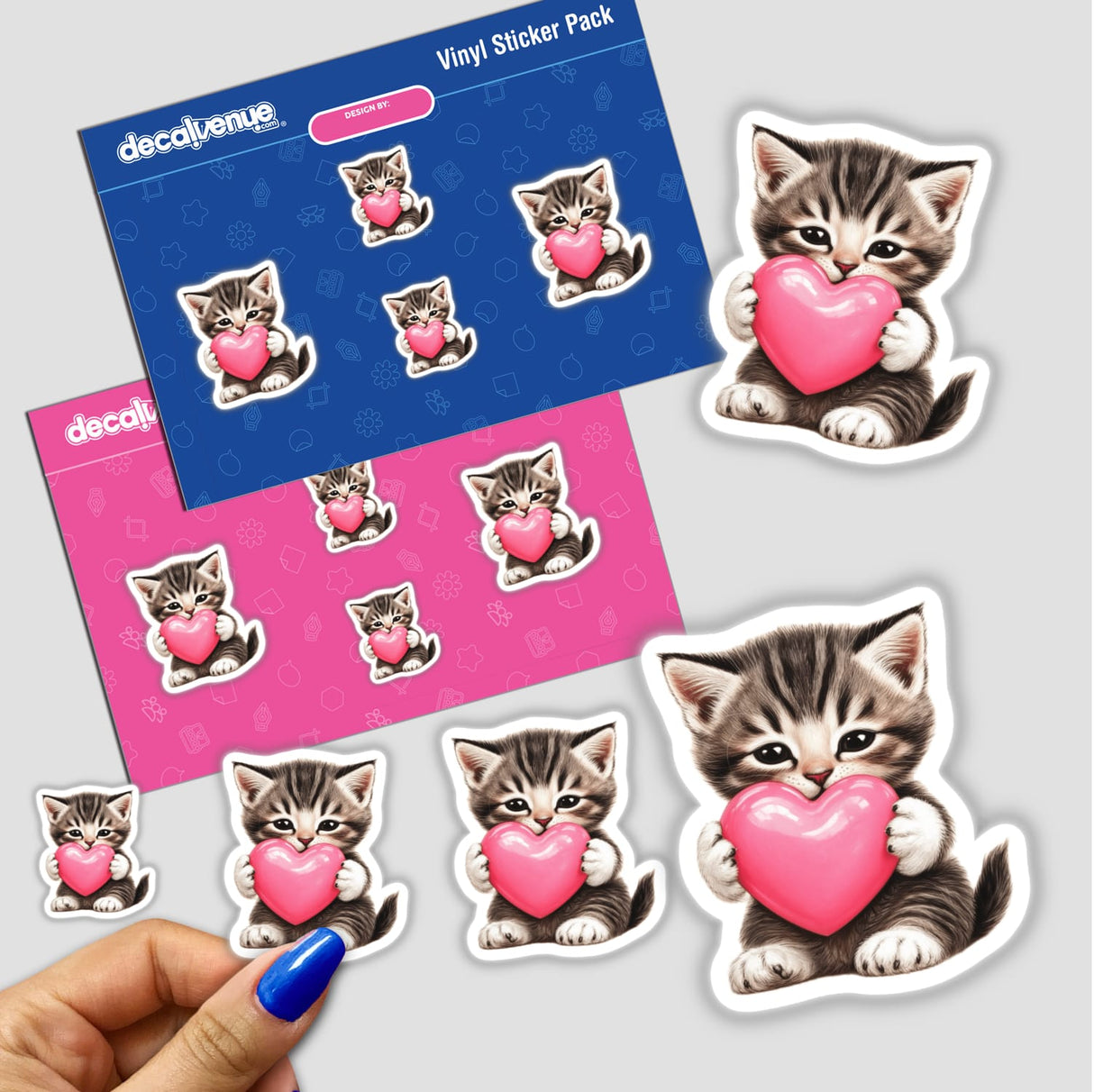 Tabby Kitten Holding Pink Heart stickers, featuring playful cartoon cats embracing hearts, available as vinyl decals or digital artwork from Decal Venue. Perfect for adding charm to your collection.