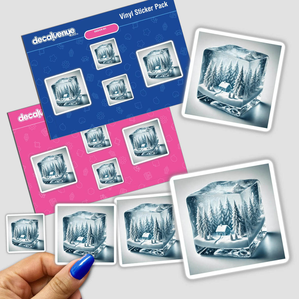 Hand holding a sticker pack featuring Winter’s Heart - Frozen Forest Inside an Ice Cube, showcasing a serene cabin scene encapsulated in a glass cube, perfect for winter-themed decor.